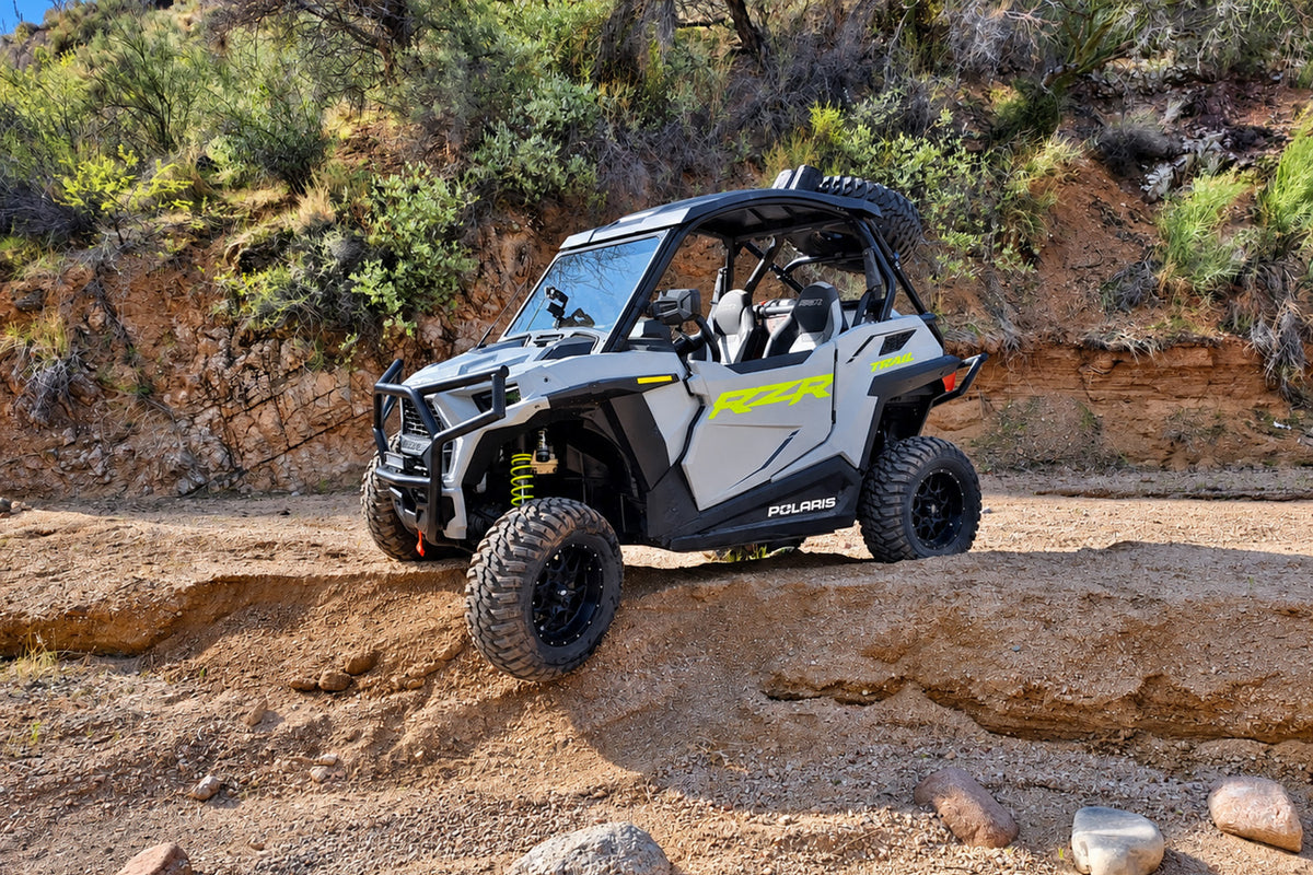 Polaris RZR Trail 900 with PERFEX 2-inch bracket lift kit driving on rugged off-road terrain.