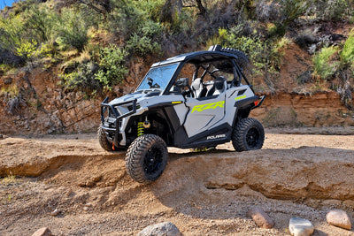 Polaris RZR Trail 900 with PERFEX 2-inch bracket lift kit driving on rugged off-road terrain.